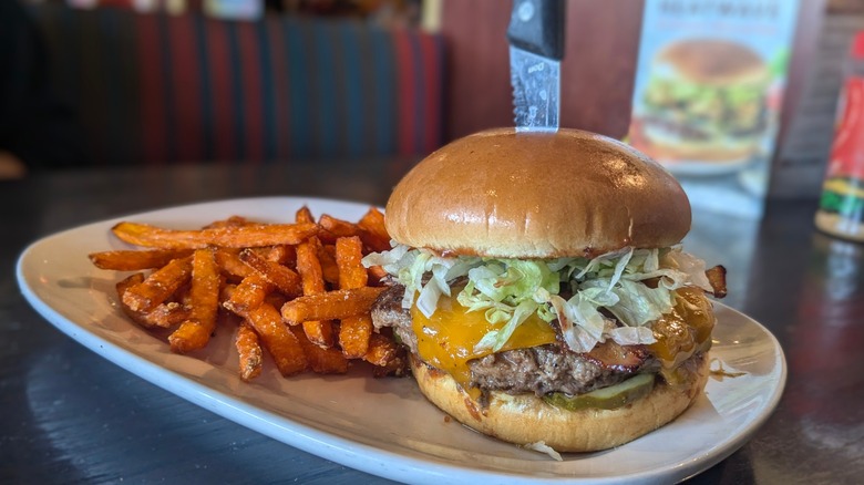 Burger with sweet potato fries on the side on white plate