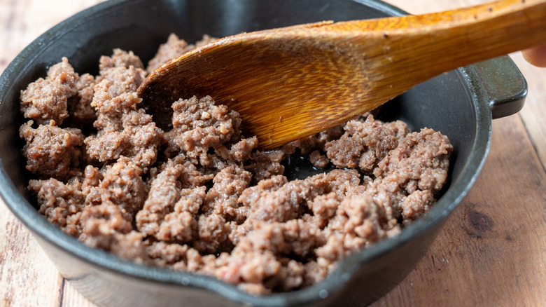 Closeup of a pan of ground beef with a wooden spoon