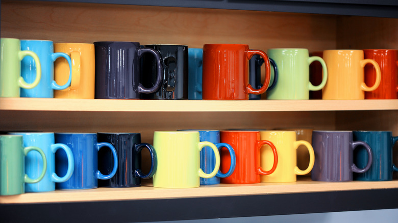 Colorful coffee mugs lined up on shelves