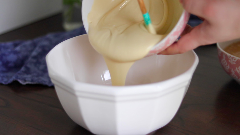 Sweetened condensed milk in bowl, being poured into another