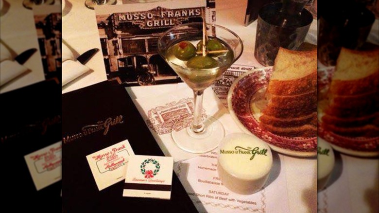 Martini on a table at Musso & Frank Grill with branded butter, matches, and postcards