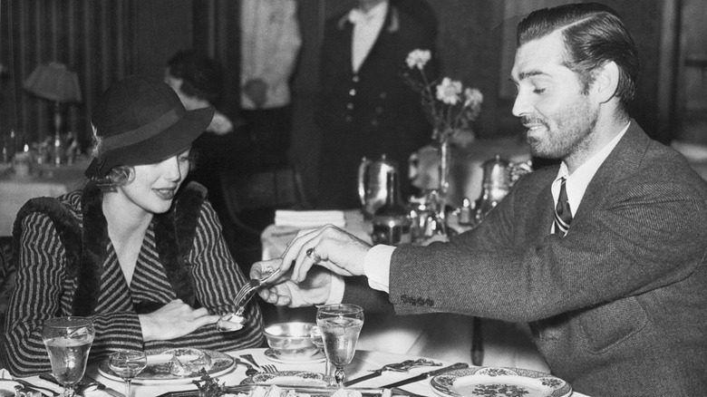 Black and white photo of Clark Gable and Loretta Young at restaurant table