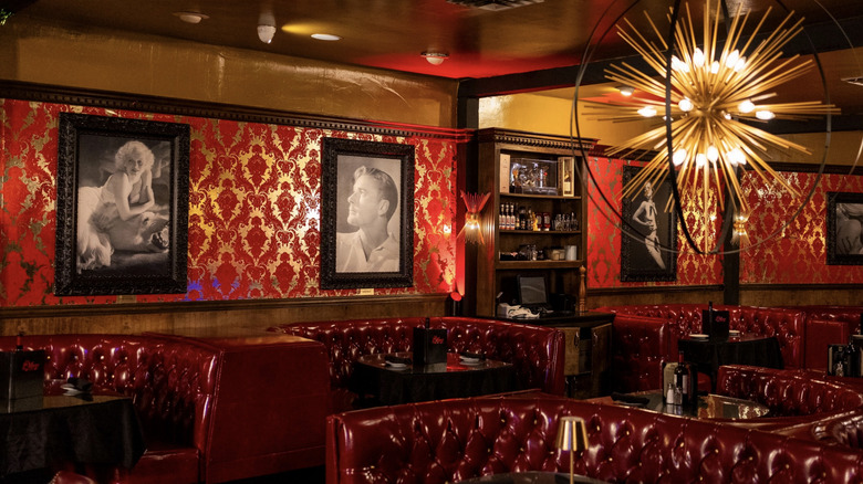 Banquette table and portraits on wall beside booths inside Cafe La Maze