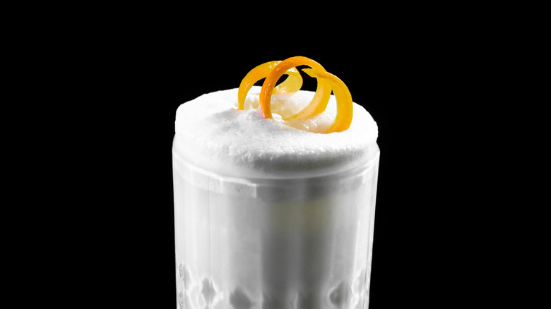 foamy top of a gin fizz cocktail with an orange rind twist on top.