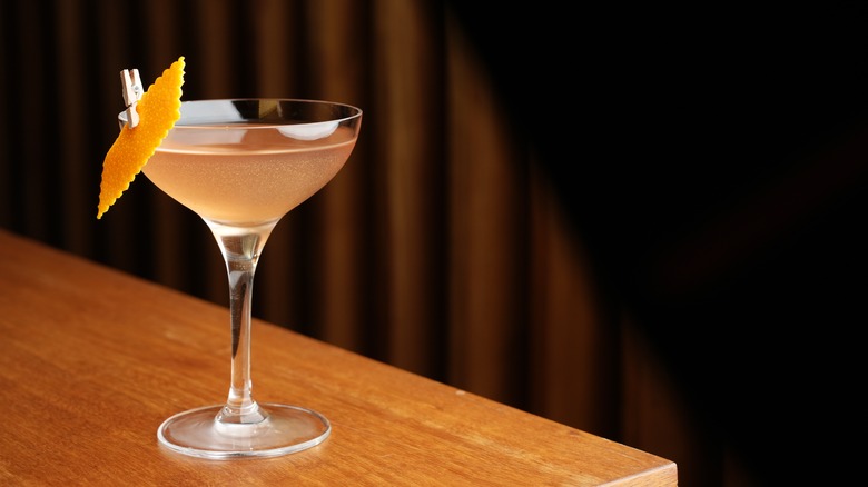 The Bronx cocktail in glass garnished with orange peel on wooden table