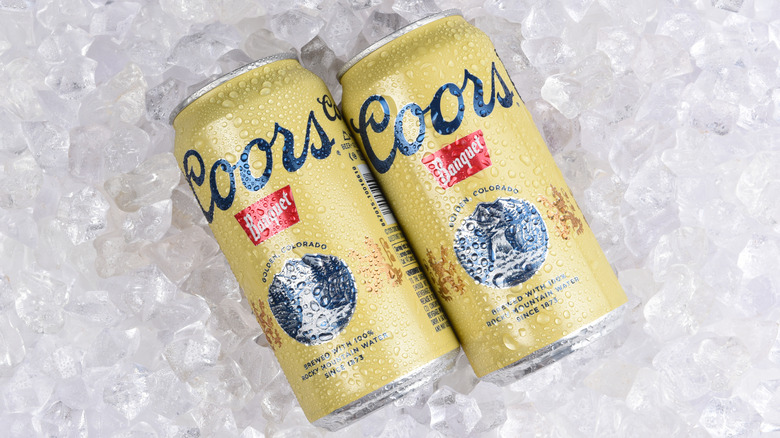 Two cans of Coors Banquet beer on ice