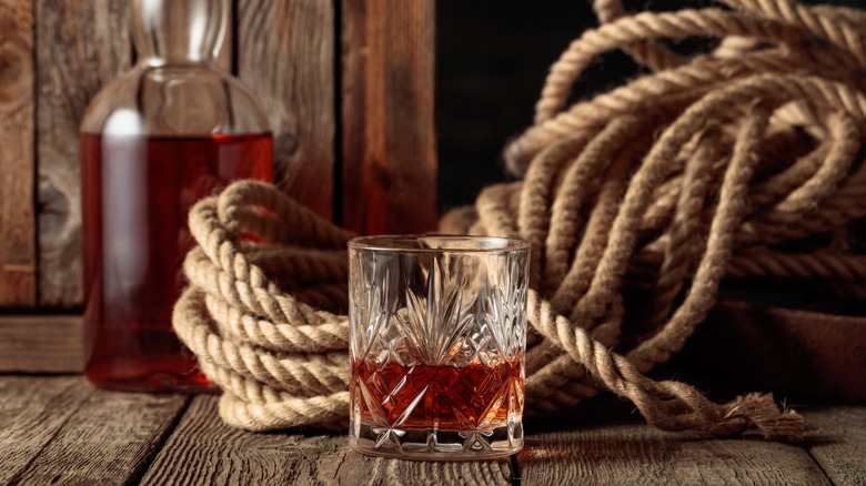 glass of bourbon with rope and bottle behind