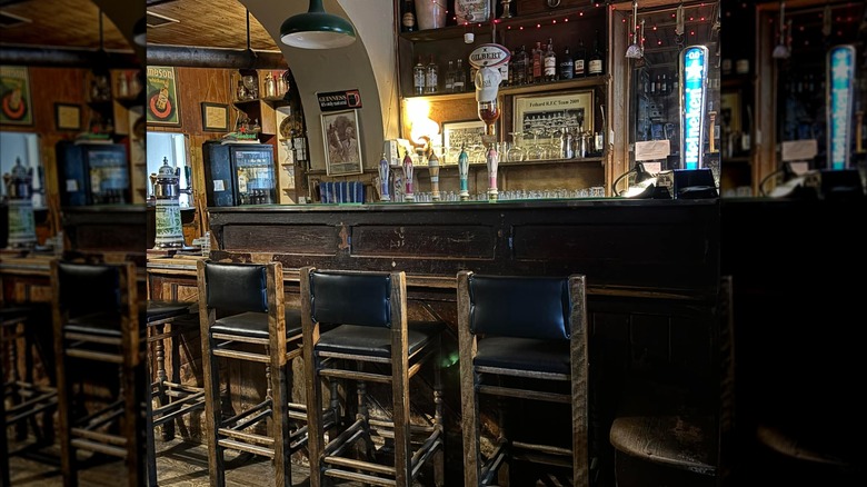 Dark wood bar with green leather stools in McCarthys Fethard
