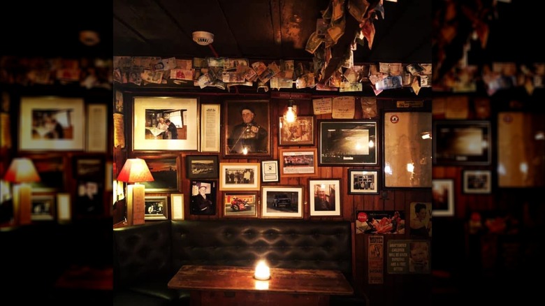 Table with a candle and a wall with photos and paper money in Olde Glen Bar