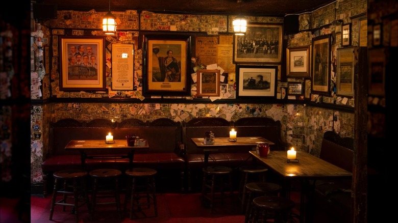 Dimly lit room with photos on the wall and tables with candles at The Brazen Head