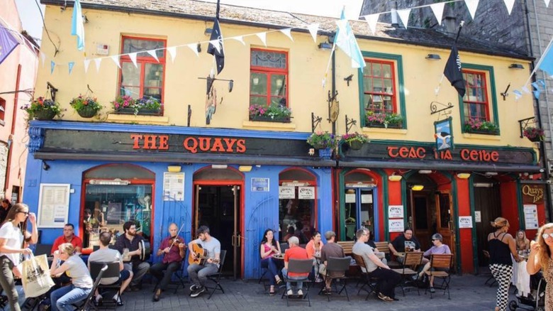 People sitting outside The Quays with musicians playing
