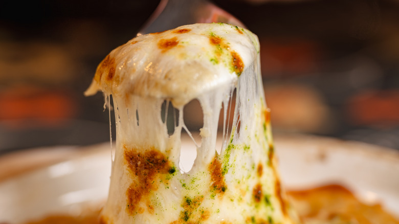 an epic cheese pull from a  slice of pizza being lifted from the pie