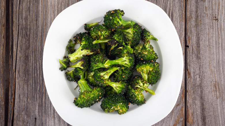 Garlic parmesan-seasoned broccoli in a white bowl, on a wooden table