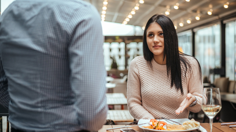 A customer gesturing at a plate of food while talking to a server