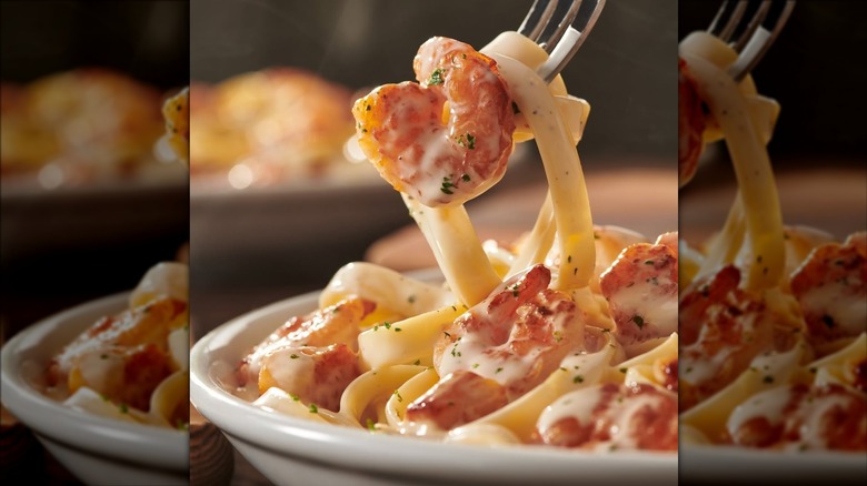 Plate of Olive Garden shrimp carbonara with fork lifting noodles and piece of shrimp upward