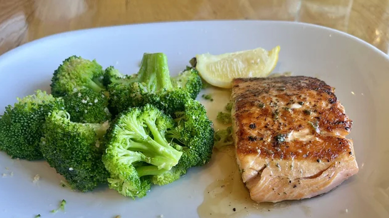A plate of the herb-grilled salmon and parmesan broccoli with a lemon wedge at Olive Garden