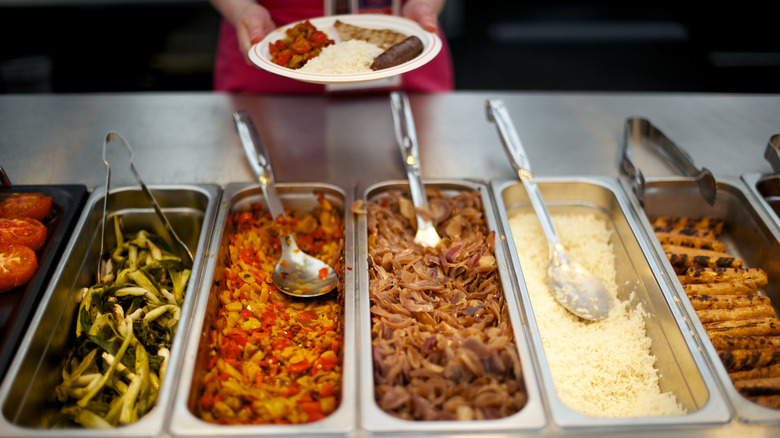 Trays of food with serving spoons on display the London Olympic Village dining hall