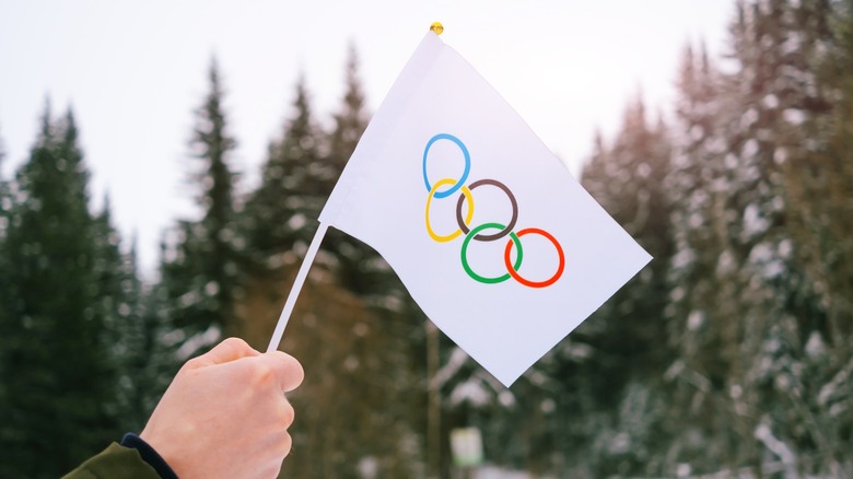 Hand holding Olympic flag snow