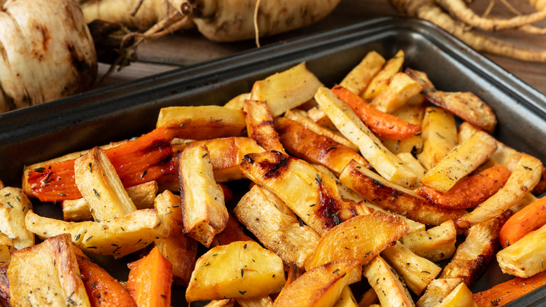 Close-up of oven-roasted parsnips on a baking sheet with herbs