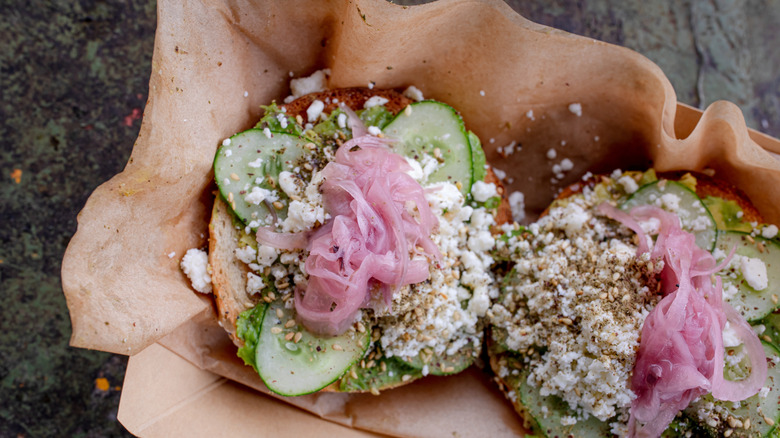 Open-faced bagel with feta, pickled onions, za'atar, and cucumbers