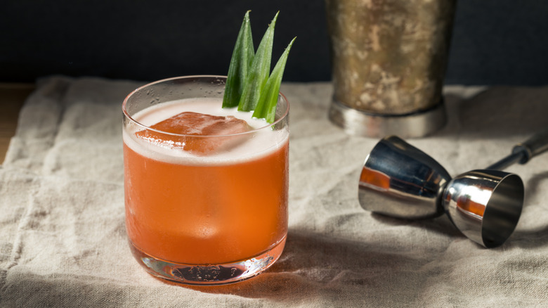 glass of rum punch cocktail with a pineapple leaf garnish