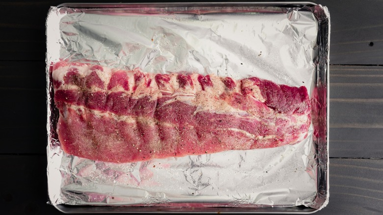 seasoned baby back ribs on a foil-lined sheet pan