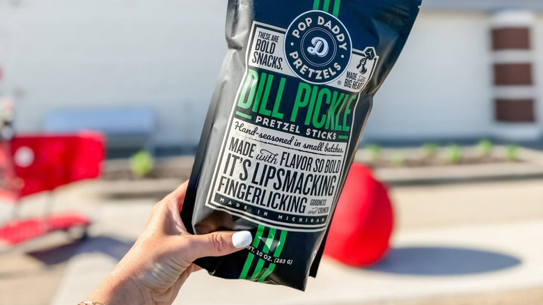 A person holding Pop Daddy Dill Pickle Pretzel Sticks
