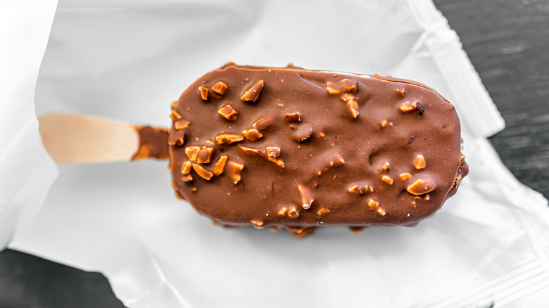 Close-up of a milk chocolate coated ice cream bar with chopped nuts