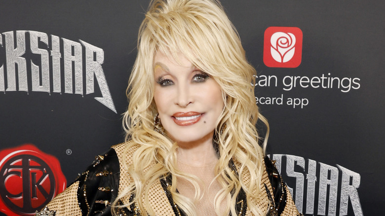 Dolly Parton smiling on a red carpet while promoting her album Rockstar