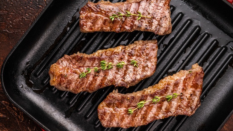 three tri tip steaks topped with herbs on a grill plate