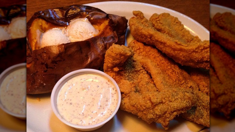 Texas Roadhouse fried catfish, sweet potatoes, and sauce on a white plate