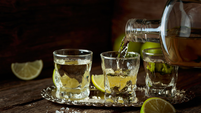 Bottle pouring tequila into two shot glasses
