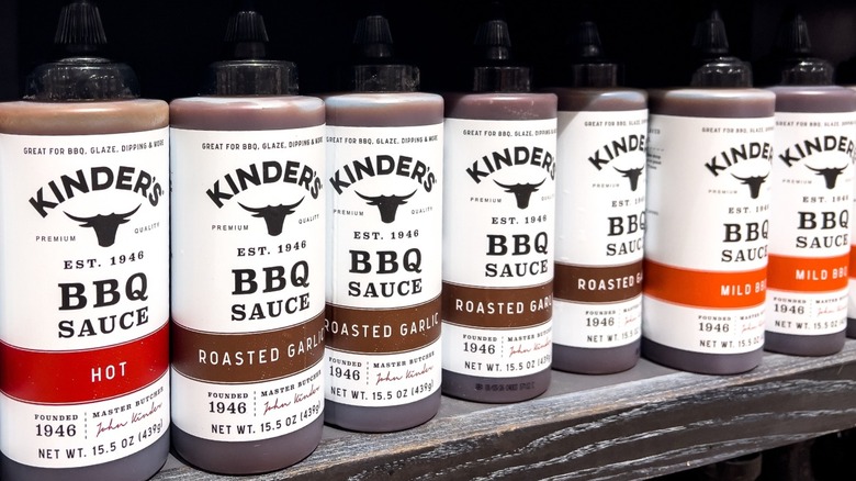 A shelf with bottles of Kinder's BBQ sauce varieties