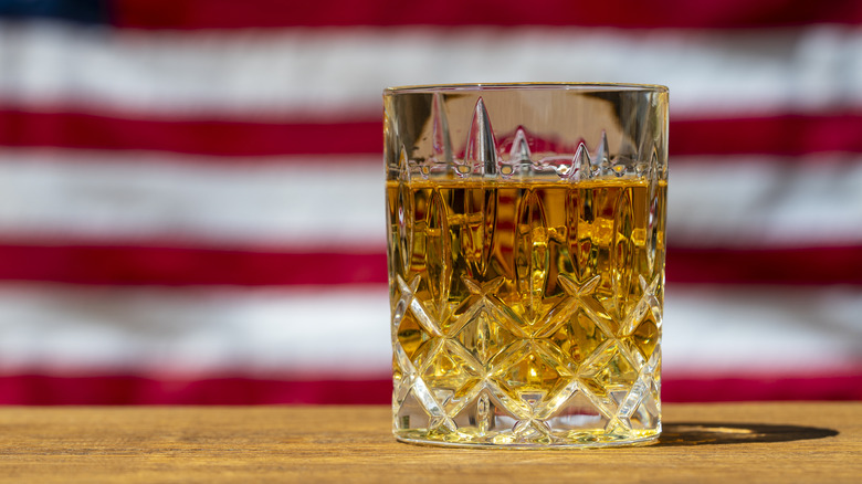 A crystal glass of bourbon in front of an American flag