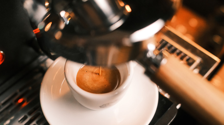 coffee being made in an espresso machine with cup visible and coffee pouring into it