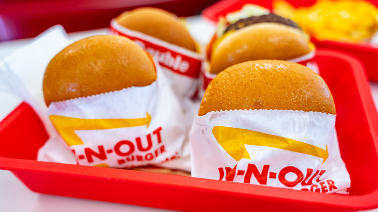 Several wrapped In-N-Out hamburgers on a red tray