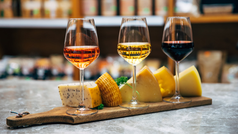 Wooden board with a display of cheeses and three wine glasses
