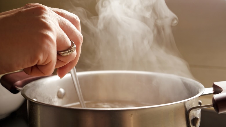 Person stirring a steaming pot of soup