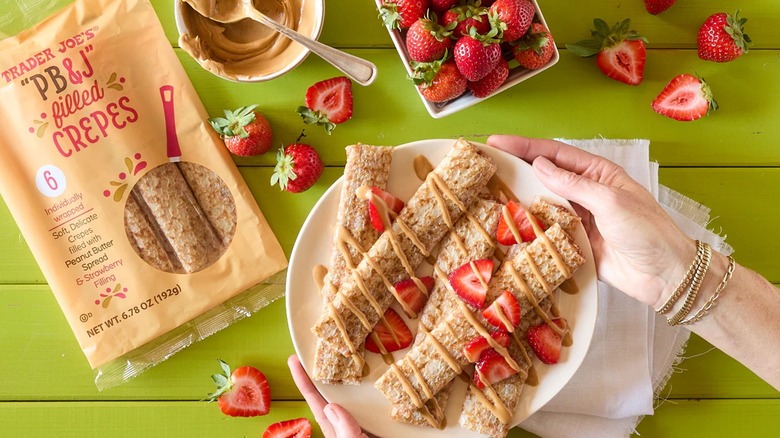 hands hold plate of Trader Joe's PB&J filled crepes with fresh strawberries