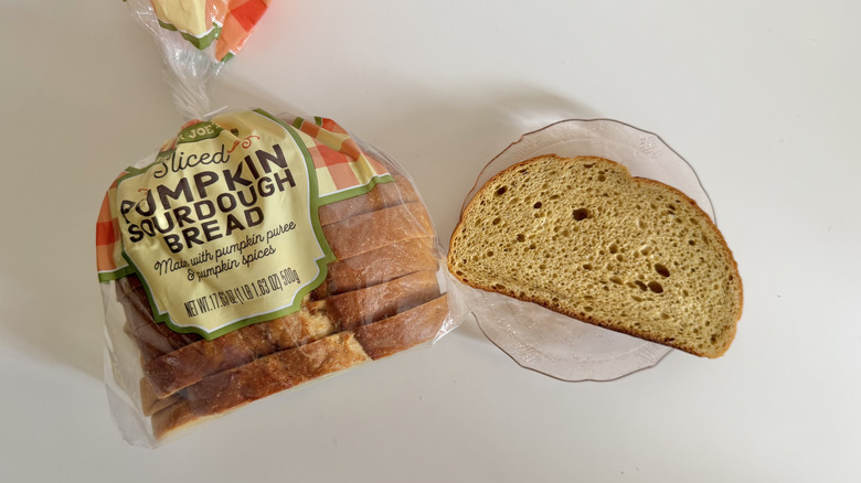 A package of Trader Joe's Sliced Pumpkin Sourdough Bread on a kitchen counter next to a plate with the bread.