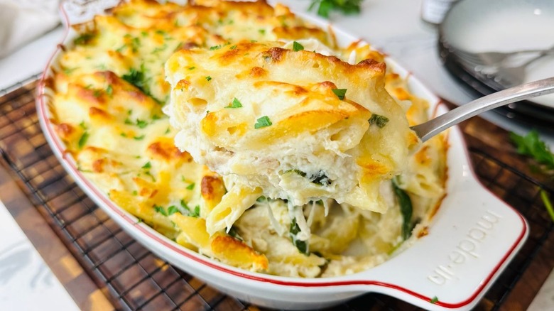 Scoopful of chicken Alfredo being removed from baking dish
