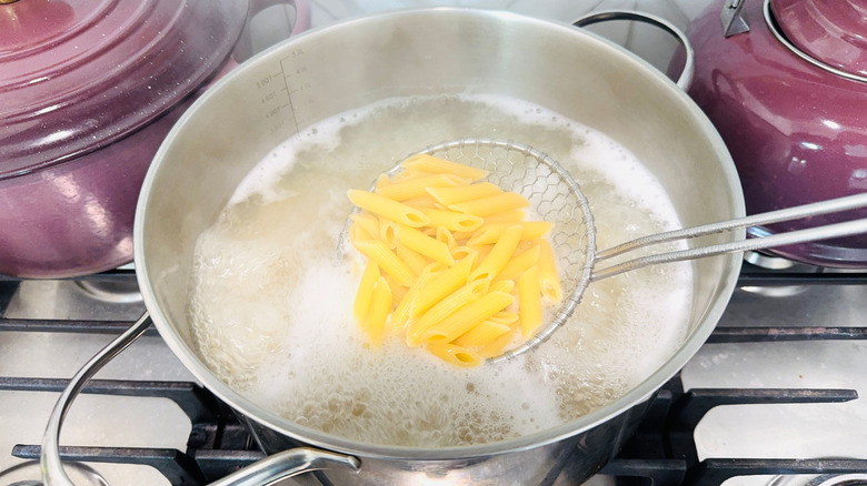 Strainer holding penne over boiling water