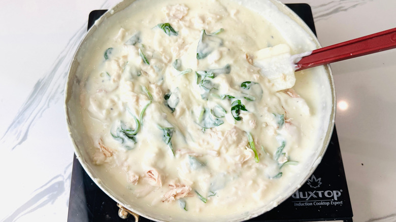 Alfredo sauce with spinach and chicken in pan