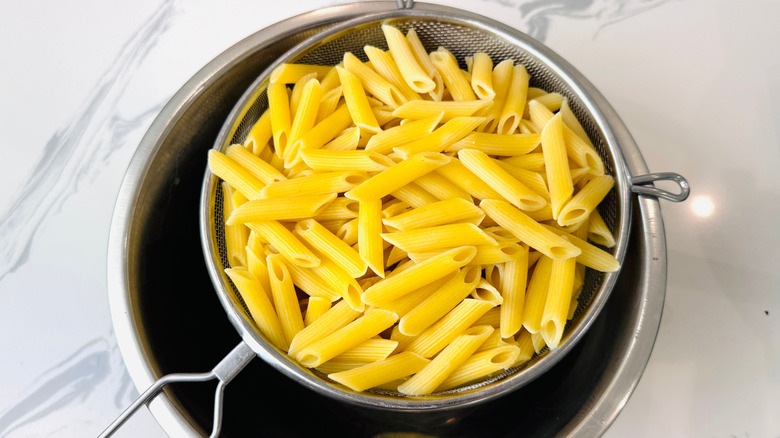 Penne sitting in strainer over pot