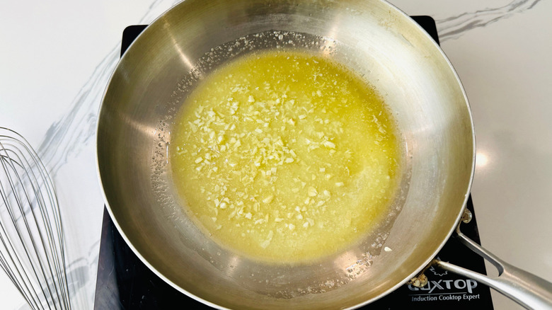 Minced garlic cooking in melted butter in pan