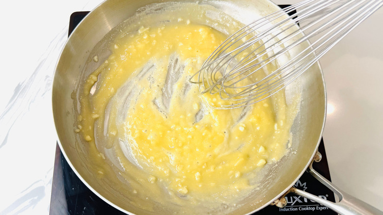 Whisk mixing garlic and flour in pan