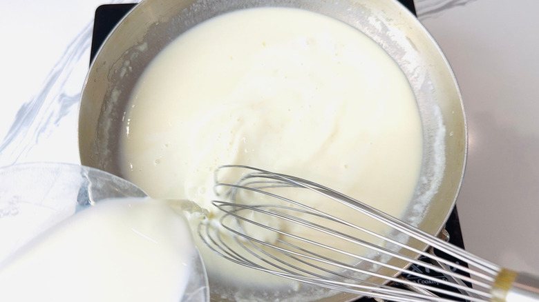 Milk pouring into pan while whisking