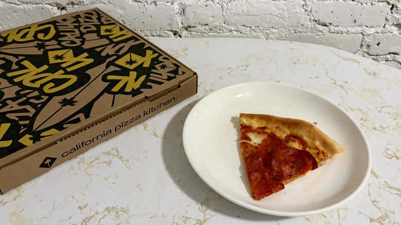 pizza slice from California Pizza Kitchen served on plate with pizza box besides