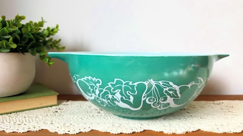 A vintage teal Pyrex Fruit Salad or Hidden Baby bowl featuring a white design of leaves and fruits
