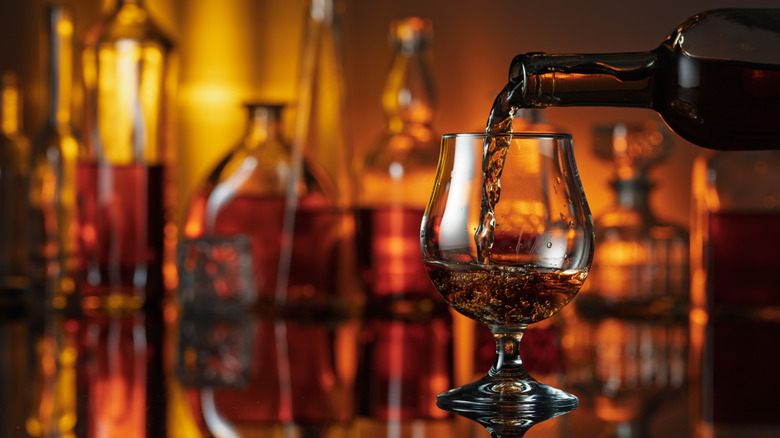 Bourbon in a glass with bottles behind